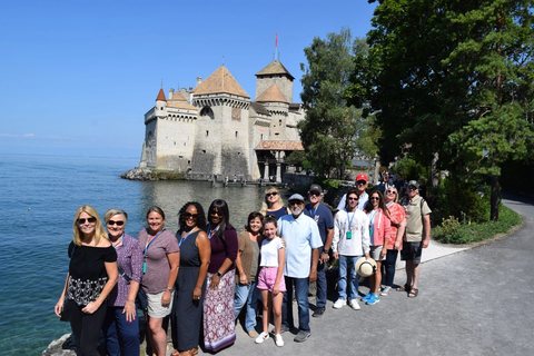 A MyTribe group gathered on the lawn in front of a lakeside castle, arms around each other.