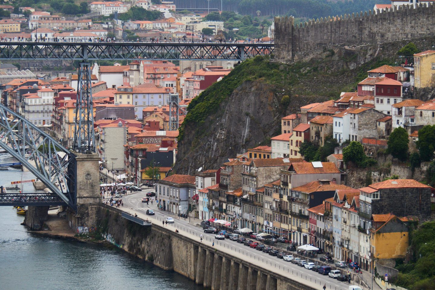 The terracotta rooftops of Porto&rsquo;s Ribeira stacked above the Douro, beneath the ironwork of the Dom Lu&iacute;s I bridge.