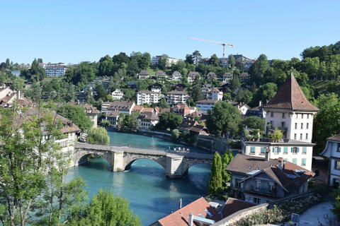 A river running under a stone bridge through an old European town, houses stacked up the hillside.